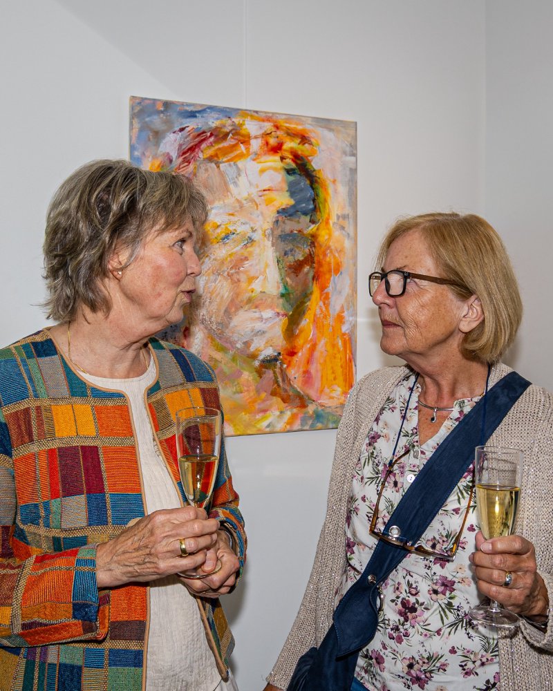 Gäste im Gespräch vor einem Porträtgemälde der Ausstellung Farben Freude