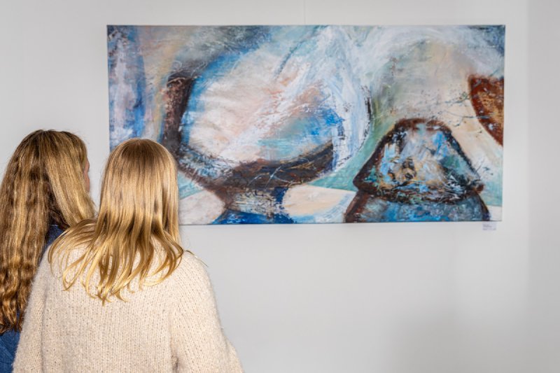 Gäste betrachten ein Werk der Ausstellung Farben Freude