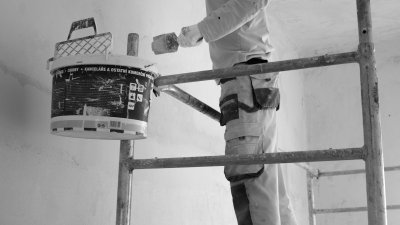 Person beim Streichen einer Wand mit Farbroller